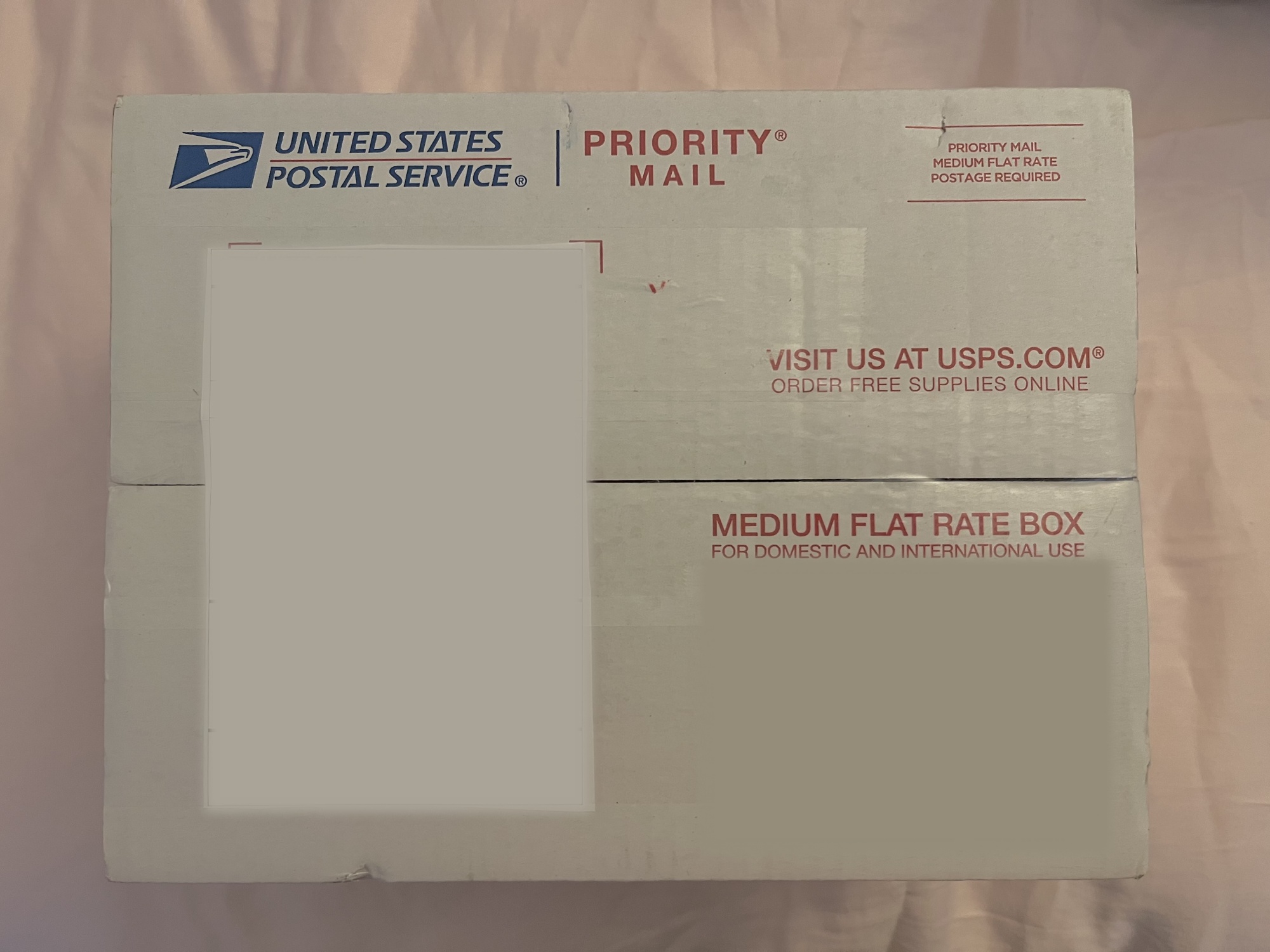 A photograph of a Priority FlatRate Mail box. The identifying information has been blurred.