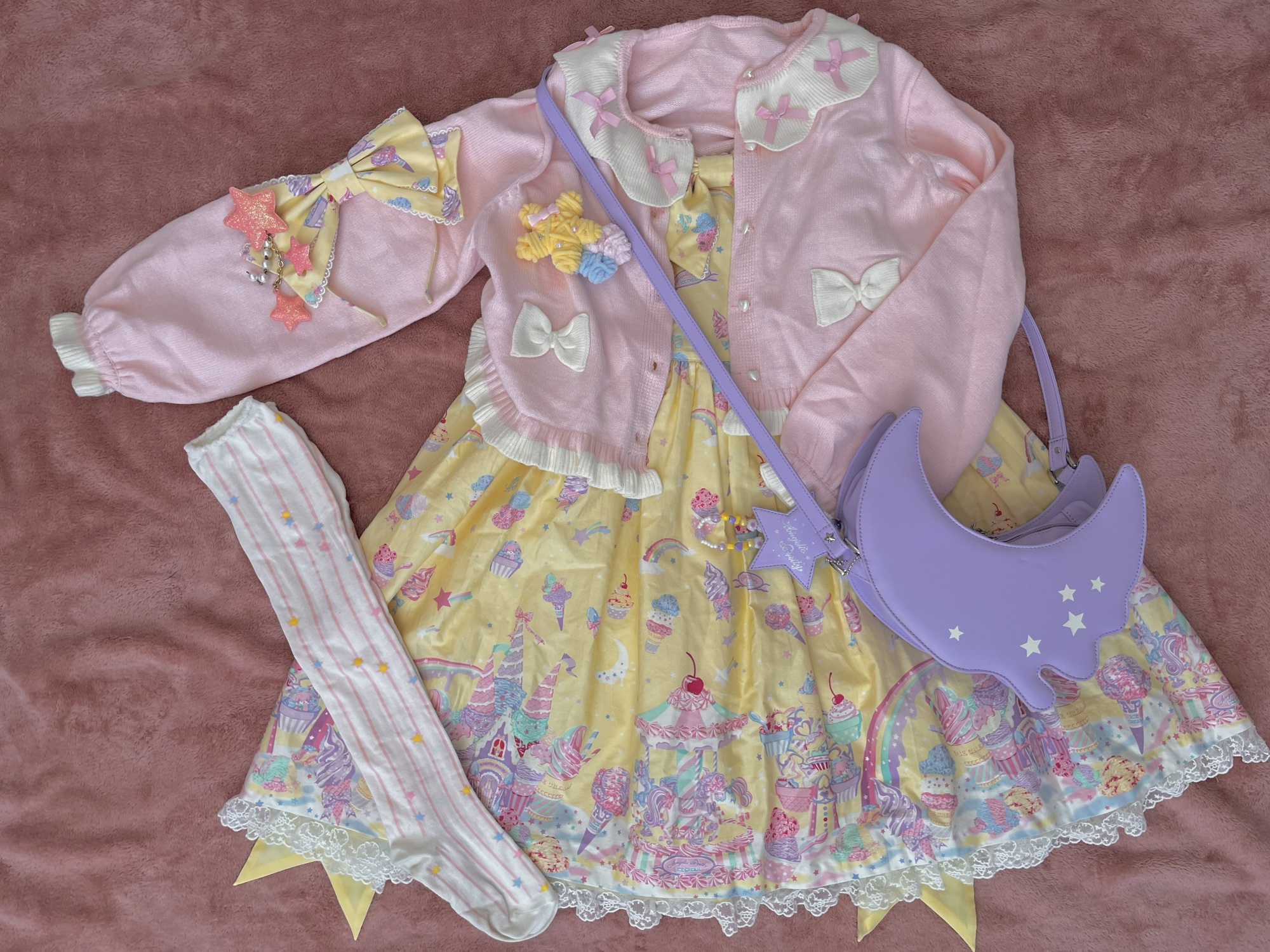 A flatlay of my Milky Planet coord, with the pink cardigan, purple bag, and other accessories like socks and hairclips visible.