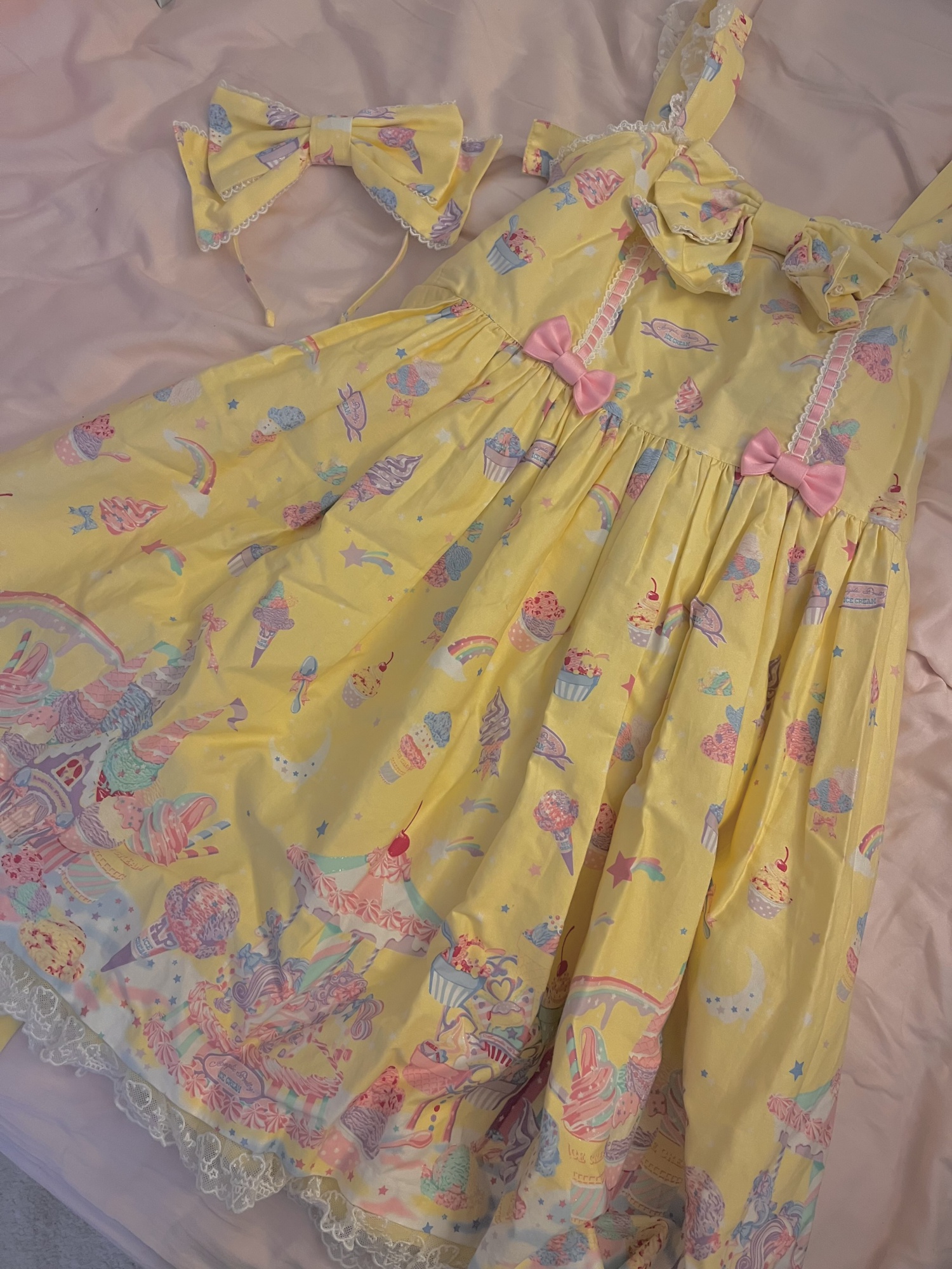 A photograph of the Milky Planet dress and headbow, which are yellow with a pastel-rainbow print of ice cream and stars.