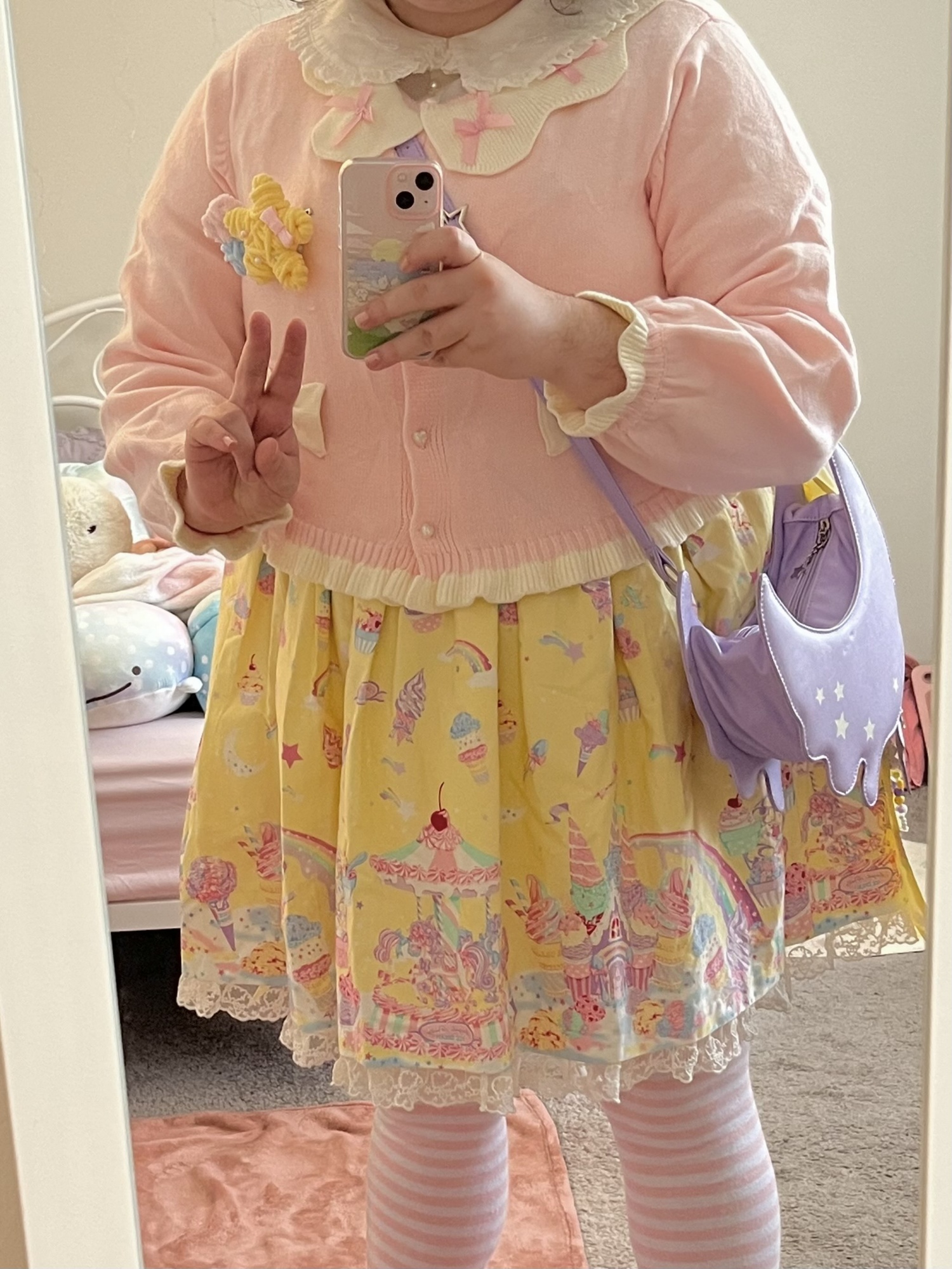 Another selfie of me wearing Milky Planet alongside a pink cardigan and purple bag. My head is not visible in the photo. I am giving a peace sign in the photo.